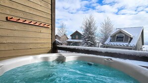 Ein Whirlpool mit einer Holterrasse und Blick auf Häuser und Bäume.