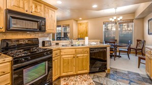 A kitchen with wooden cabinets, a stove, microwave, and a dishwasher. - Spacious family condo with  jetted tub, ideal location, & free WiFi (Park City)