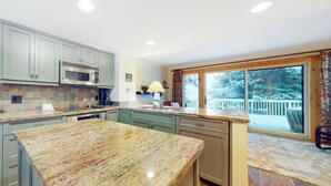 A kitchen with granite countertops, a built-in microwave, and a large window overlooking a snowy deck. - Three-story townhome with fireplace & decks - steps to shuttle & rec center (Park City)