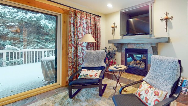 A cozy living room with two rocking chairs, a fireplace, and a large window overlooking a snowy deck. - Three-story townhome with fireplace & decks - steps to shuttle & rec center (Park City)