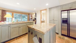 A kitchen with granite countertops, a stainless steel refrigerator, and a window with curtains. - Three-story townhome with fireplace & decks - steps to shuttle & rec center (Park City)