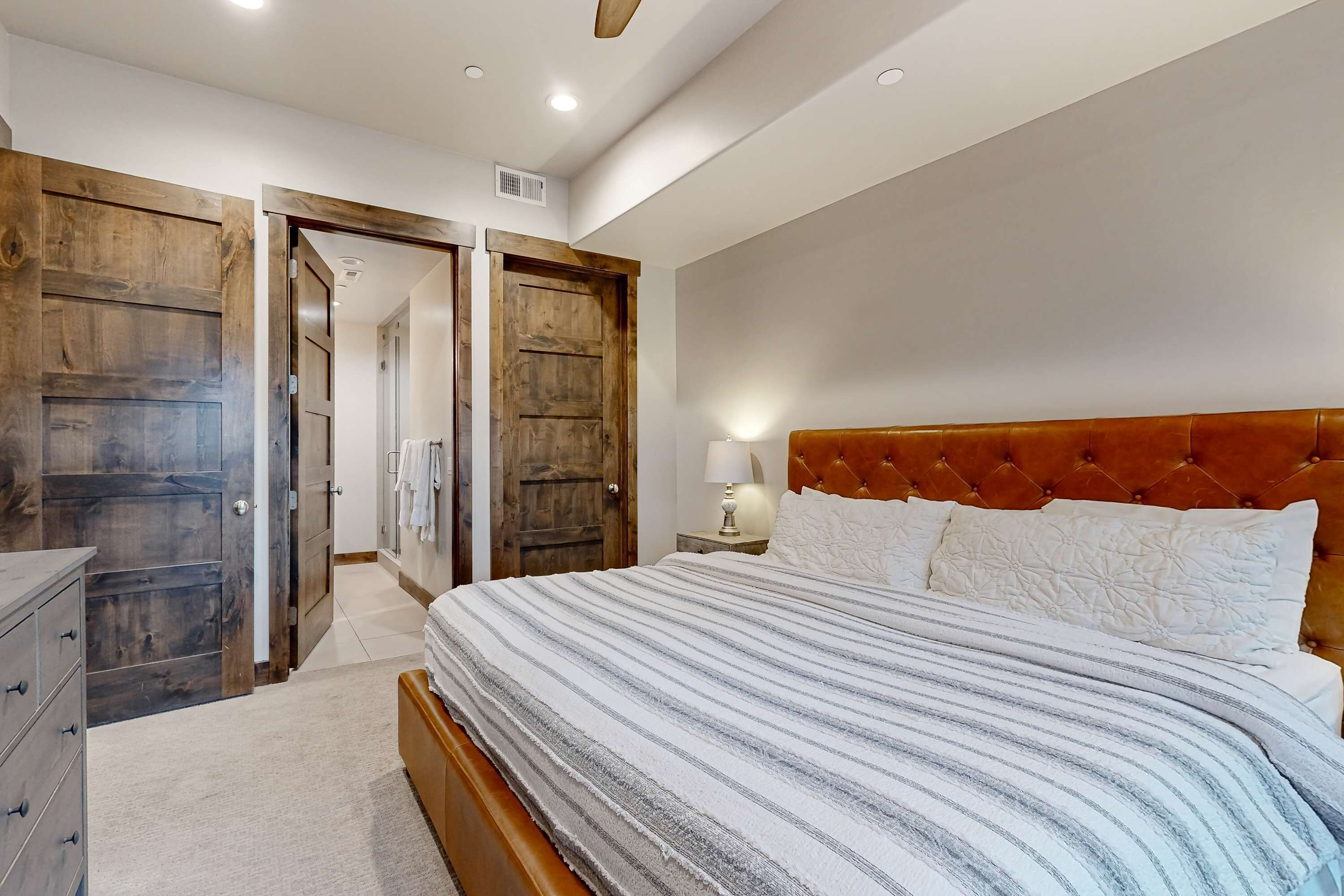 Ein Schlafzimmer mit einem Bett, einem Holzschrank und einer Tür zu einem anderen Raum.