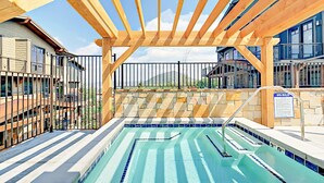 Una piscina con una pérgola de madera, muros de piedra y un cartel que indica las normas del spa.