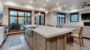 Una cocina moderna con una isla grande, electrodomésticos integrados y amplios ventanales.