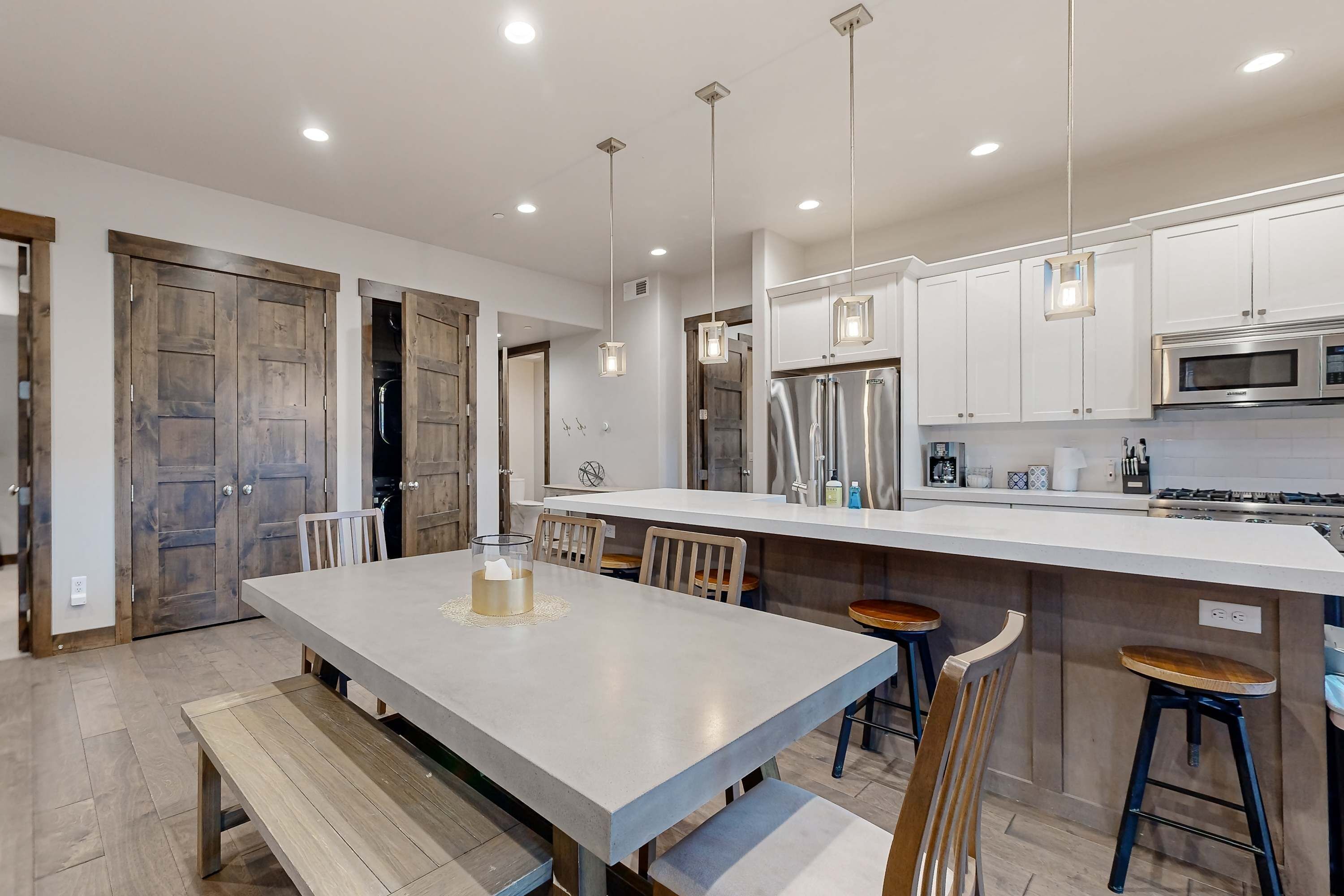 A modern kitchen with white cabinets, stainless steel appliances, and pendant lighting.