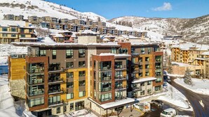 Un hôtel moderne à plusieurs étages, doté de balcons, situé dans une région montagneuse enneigée.