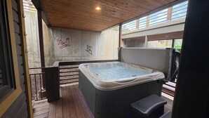 Ett bubbelbad på ett trädäck med utsikt över en byggnad i bakgrunden.