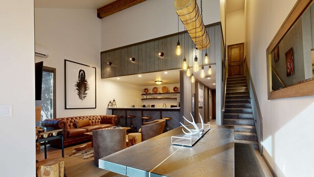 Ein modernes Interieur mit einer zentralen Kochinsel, einer Treppe und einem Essbereich.