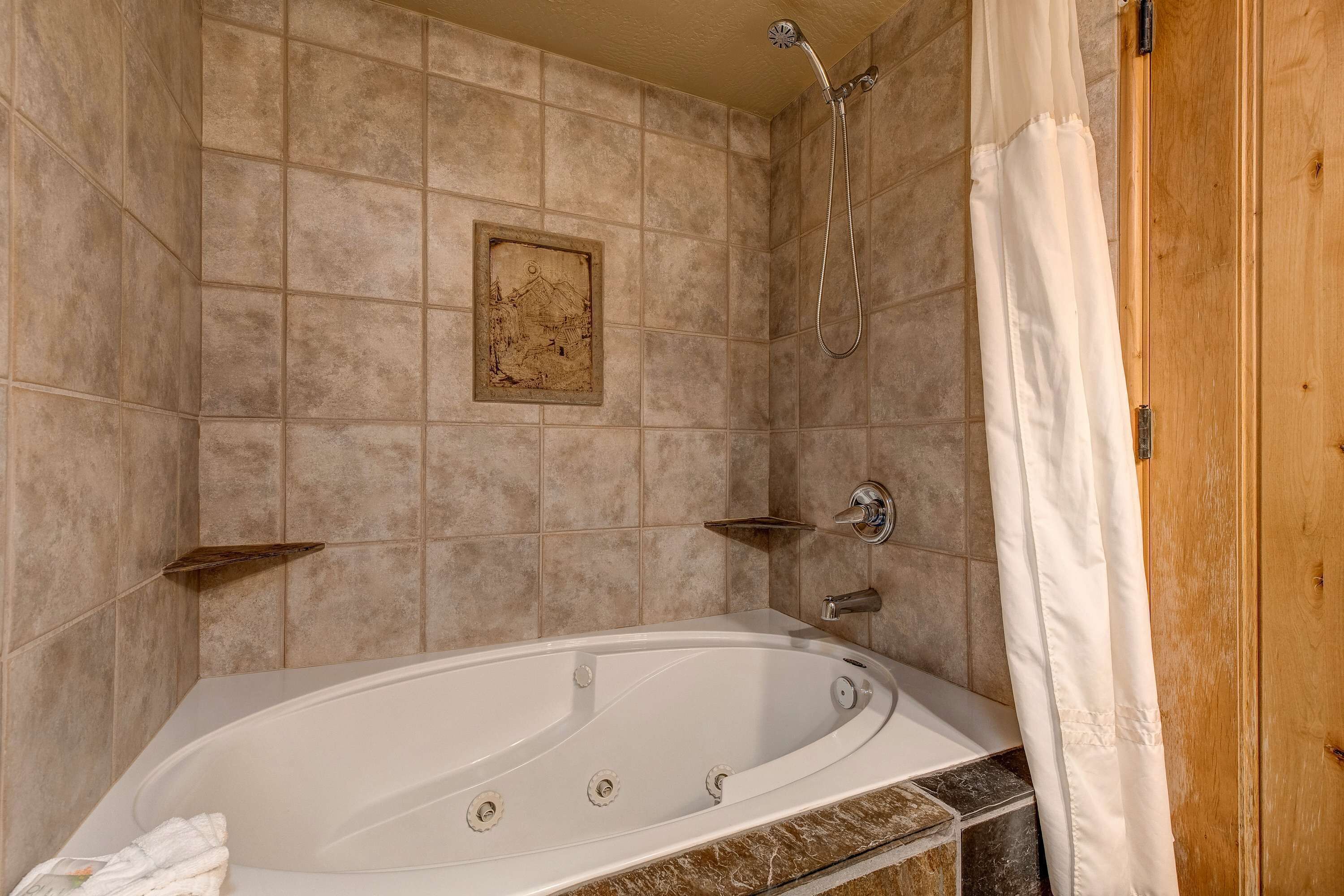 A bathroom with a bathtub, shower, and a wooden door.
