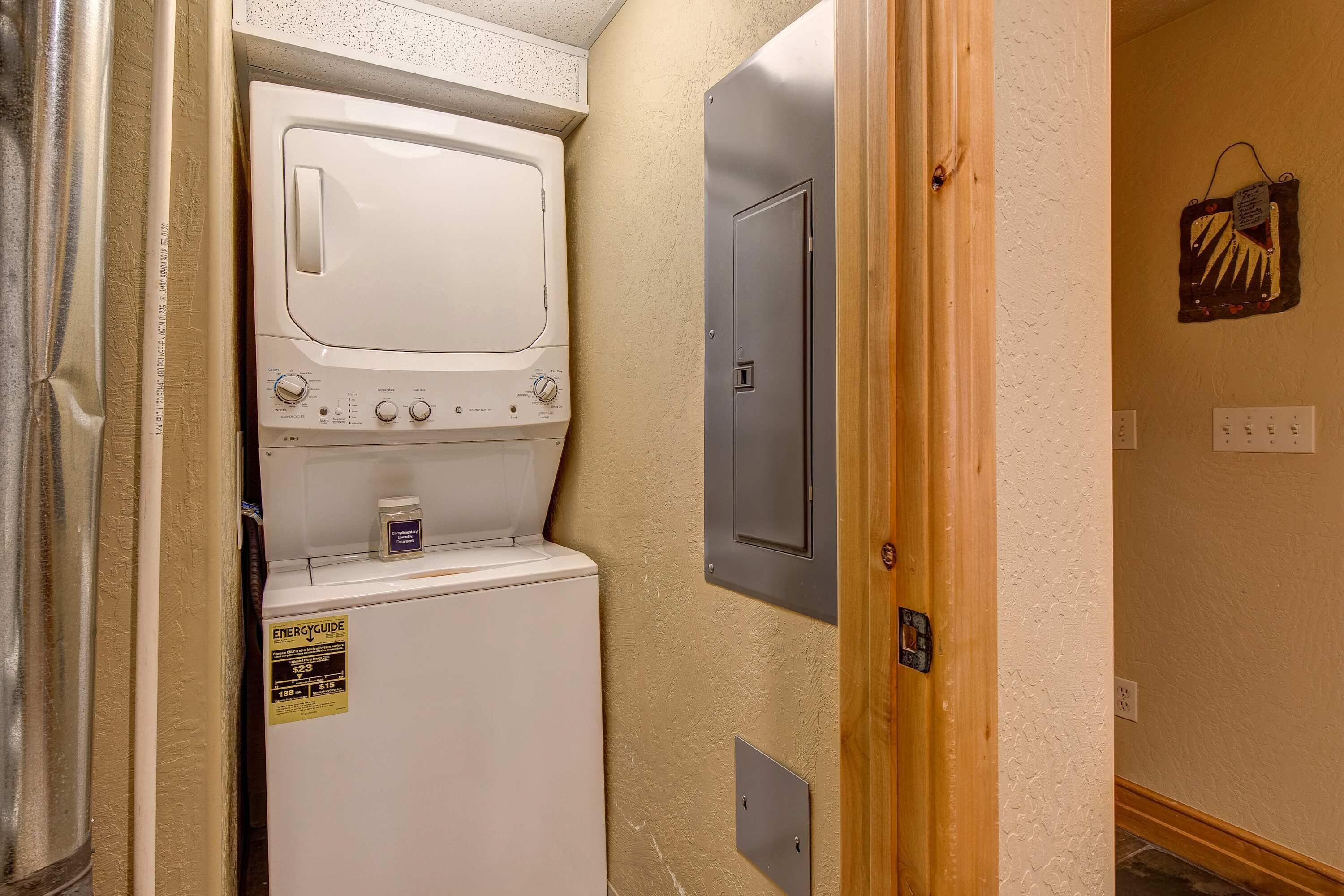 A laundry room with a washer and dryer, a door, and a wall-mounted electrical panel.
