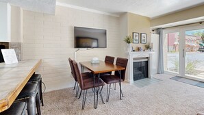 Un comedor con pared de ladrillo, un televisor de pantalla plana sobre una mesa y una chimenea.