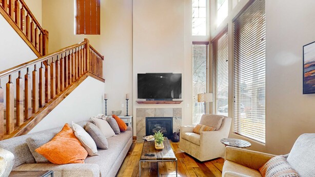 Una sala de estar con una escalera, una chimenea, un televisor y dos sofás.