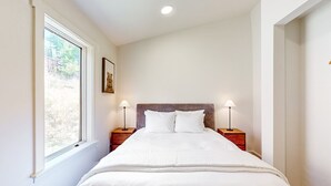 A neatly made bed with white linens, two bedside lamps, and a window with a view of trees. - Upper-level home near Main St with private hot tub, deck, ski & mtn views (Park City)