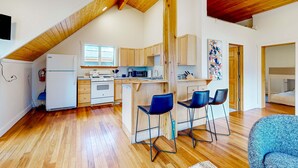 A modern kitchen with wooden cabinets, a white refrigerator, and a dining area with two bar stools. - Upper-level home near Main St with private hot tub, deck, ski & mtn views (Park City)