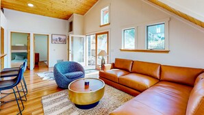 A spacious living area with a wooden ceiling, a brown leather sofa, a round coffee table, and a blue armchair. - Upper-level home near Main St with private hot tub, deck, ski & mtn views (Park City)