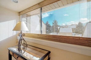 A room with a large window, a table with a lamp, and a view of a snowy landscape. - Lovely condo with fireplace, WiFi, washer & dryer - great location (Park City)