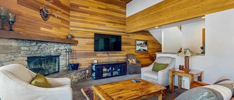 Un salón acogedor con chimenea de piedra, techo de madera y asientos cómodos.