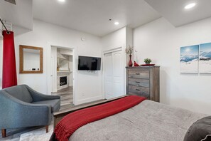 Ein Schlafzimmer mit Bett, Sessel, Fernseher, Kleiderschrank und Kamin.