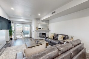 Un salon moderne avec une cheminée, un canapé en cuir et un grand miroir.