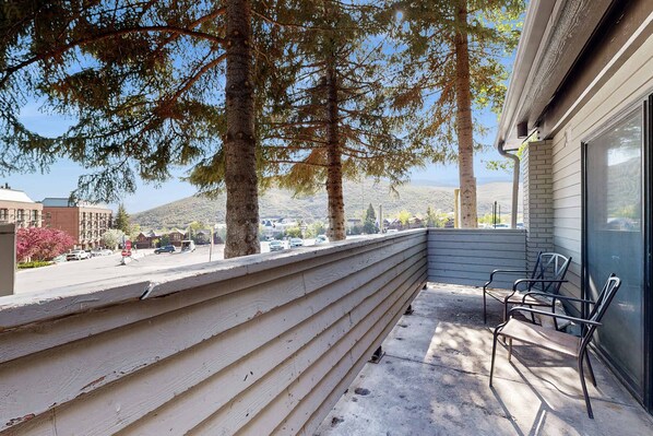 Un balcon donnant sur une rue, des arbres et un immeuble.
