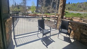A covered outdoor area with a stone wall, a metal gate, and two chairs. - Light-filled condo near Canyons Village with mountain view, pool & hot tubs (Park City)