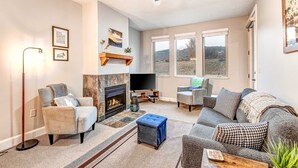 Ein Wohnzimmer mit Kamin, Sofa, Fernseher und Deckenventilator.