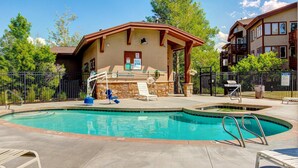 Ein Swimmingpool mit überdachtem Bereich, Liegestühlen und einem Gebäude mit Balkon.