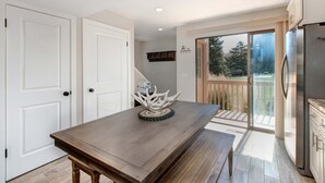 A kitchen with a wooden table, a stainless steel refrigerator, and a sliding glass door leading to a balcony. - Three-story townhome with private hot tub, gas fireplace, decks (Park City)
