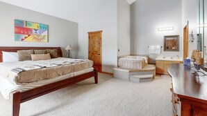 Ein Schlafzimmer mit Bett, Holztür, Badezimmer mit Badewanne und Deckenventilator.