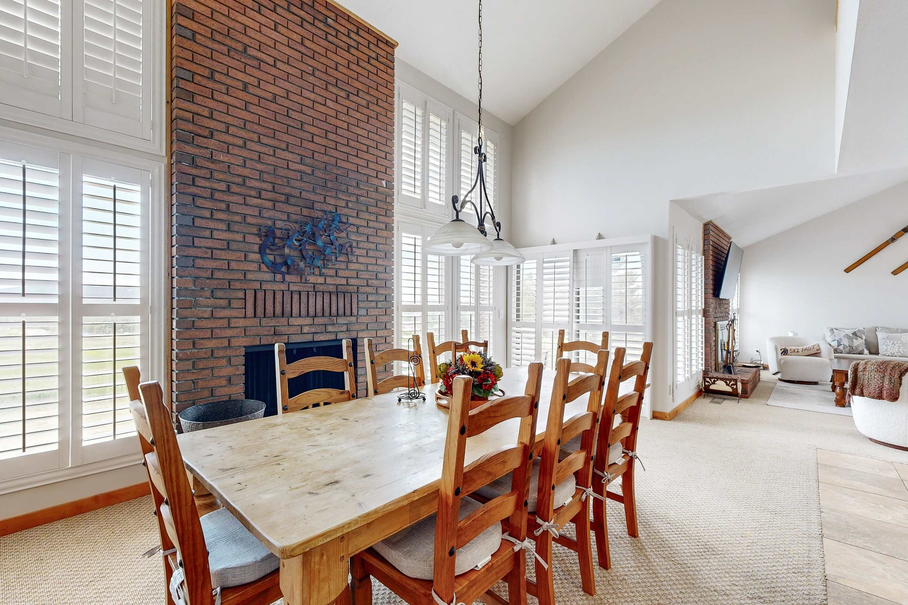 A dining area with a brick wall, large windows, and a chandelier.