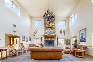 A spacious living area with a stone fireplace, leather sofas, skis, and a chandelier. - Bear Hollow Village Townhouse with  Community Pool - Ski the Slopes (Park City)