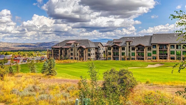 Ein mehrstöckiges Hotel mit einer großen Rasenfläche und einem Golfplatz im Hintergrund.