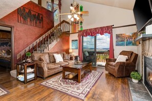 A living room with a staircase, leather furniture, a fireplace, and a scenic view. - Walk-to-lift condo with sunrise view, two lofts, pool, 2 hot tubs & tennis (Park City)