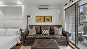Un salon moderne avec un canapé en cuir, une petite table et une grande fenêtre.