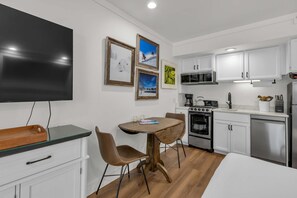 A modern kitchen with white cabinets, a microwave, stove, and a dining area with a table and chairs. - Ski-in - ski-out condo with fireplace, pool, hot tub & sauna - walk to eateries (Park City)