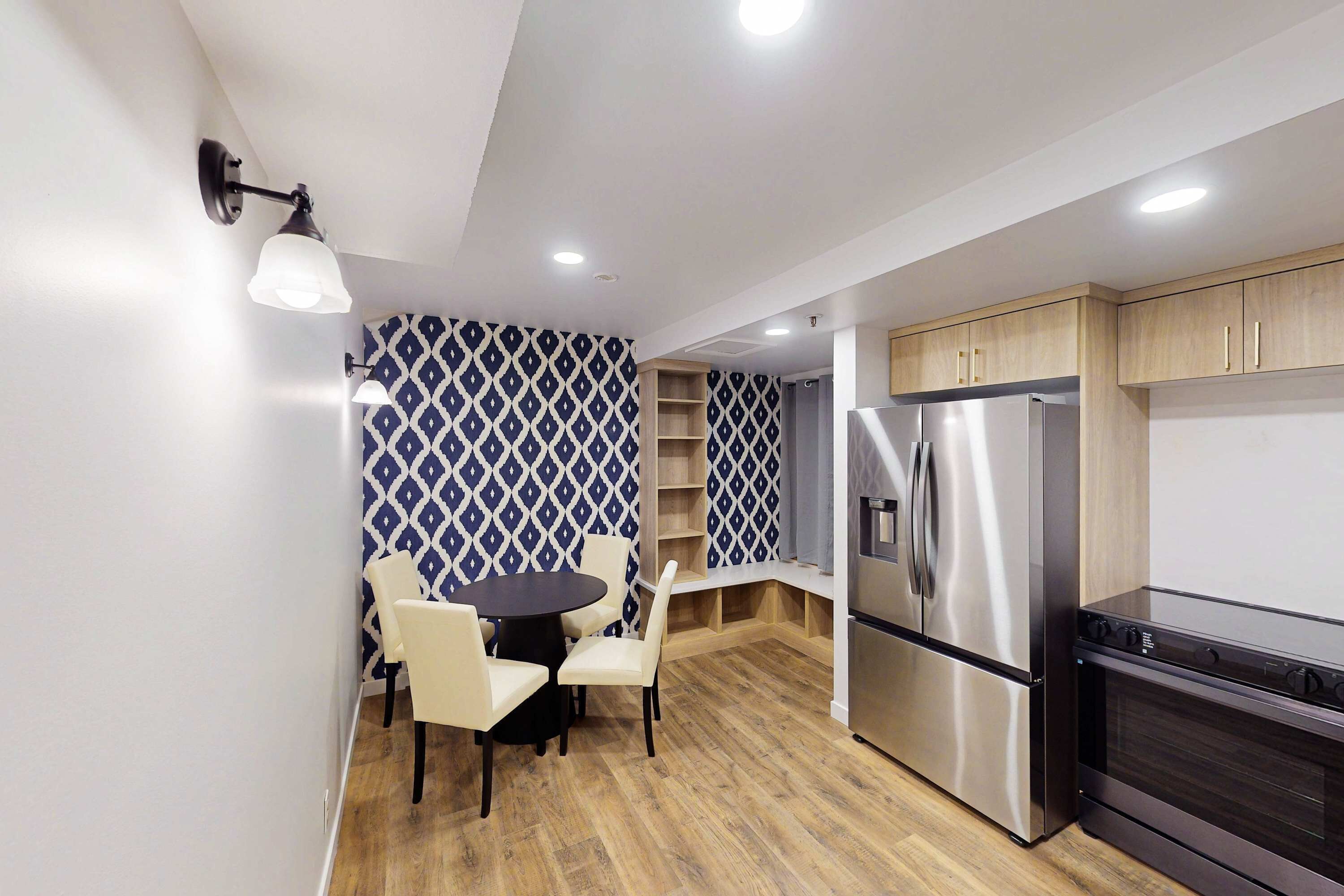 Una cocina moderna con comedor, armarios de madera, refrigerador de acero inoxidable y horno empotrado.