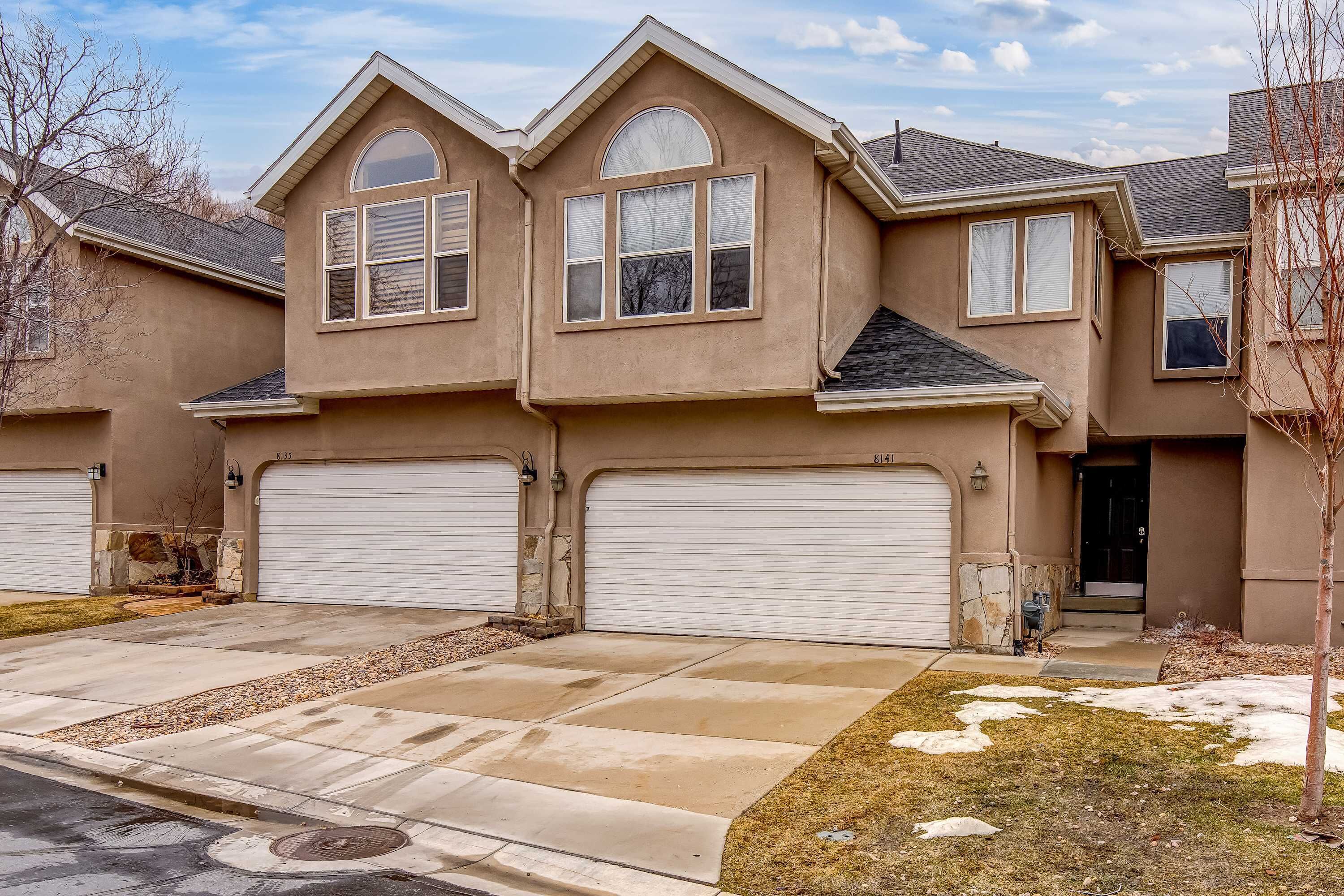 A two-story house with a garage, a driveway, and a small front yard.