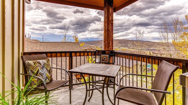 A covered patio with a table and chairs, a view of the surrounding landscape, and a wooden beam structure. - Ski view condo with fast WiFi, private grill, easy ski access, pool, & hot tub (Park City)