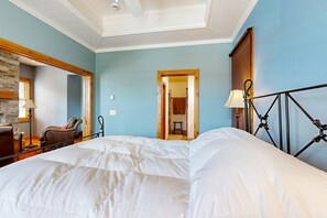 Ein Schlafzimmer mit einem großen Bett, einer Steinwand, einer Holztür und einer Lampe.