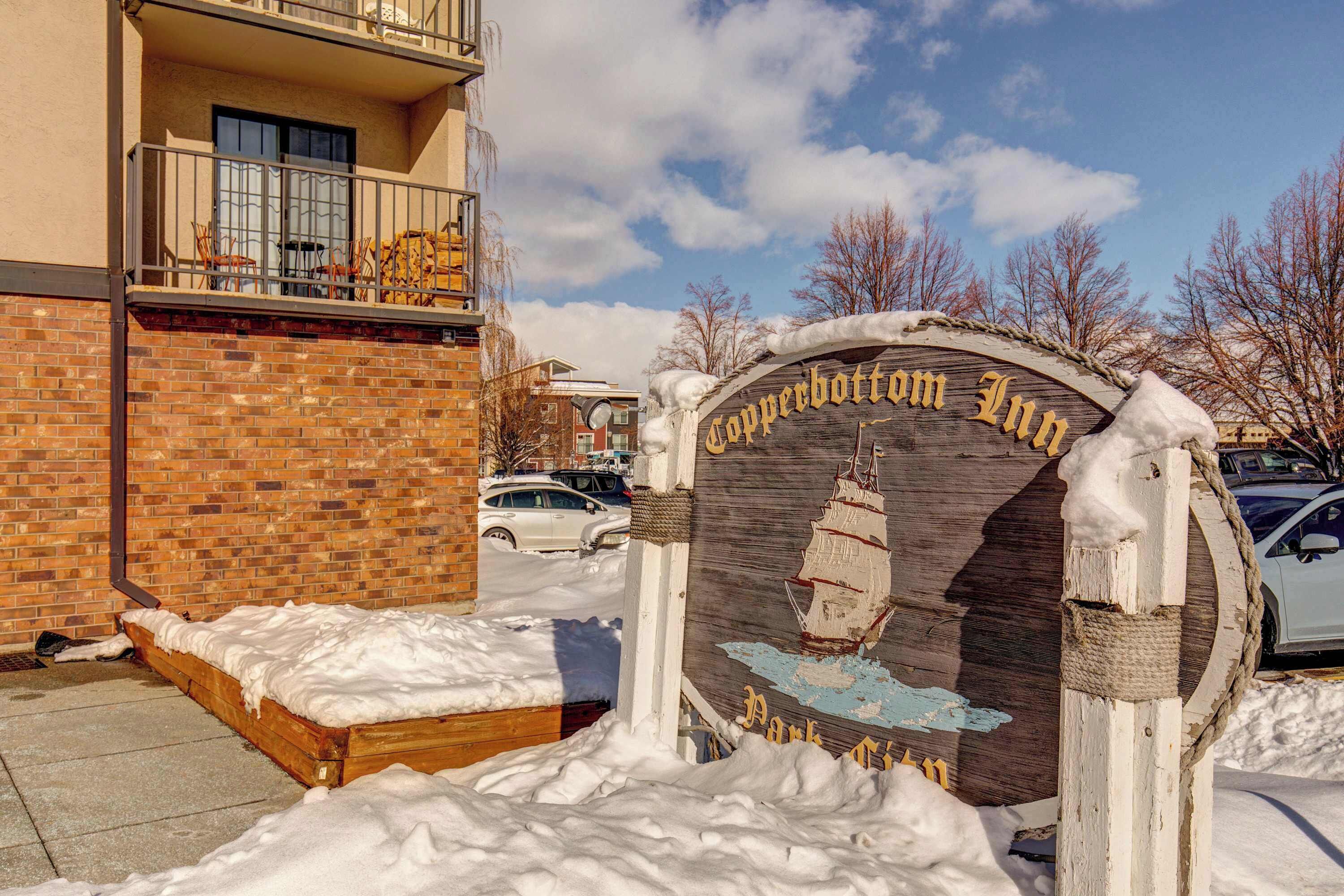 A wooden sign with a ship and the text 'Copperbottom Inn' in a snowy setting.