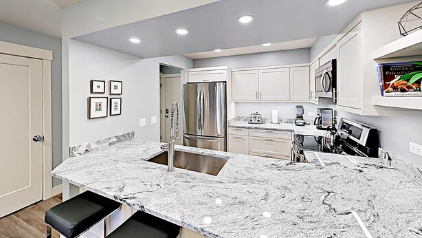 A modern kitchen with a marble countertop, stainless steel appliances, and recessed ceiling lights. - Short walk to Park City lifts (Park City)