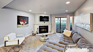 A modern living room with a fireplace, a large sofa, a television, and a painting on the wall. - Short walk to Park City lifts (Park City)