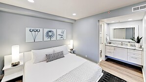 A modern hotel room with a large bed, bedside lamps, a nightstand, and a bathroom with a mirror, sink, and cabinets. - Short walk to Park City lifts (Park City)
