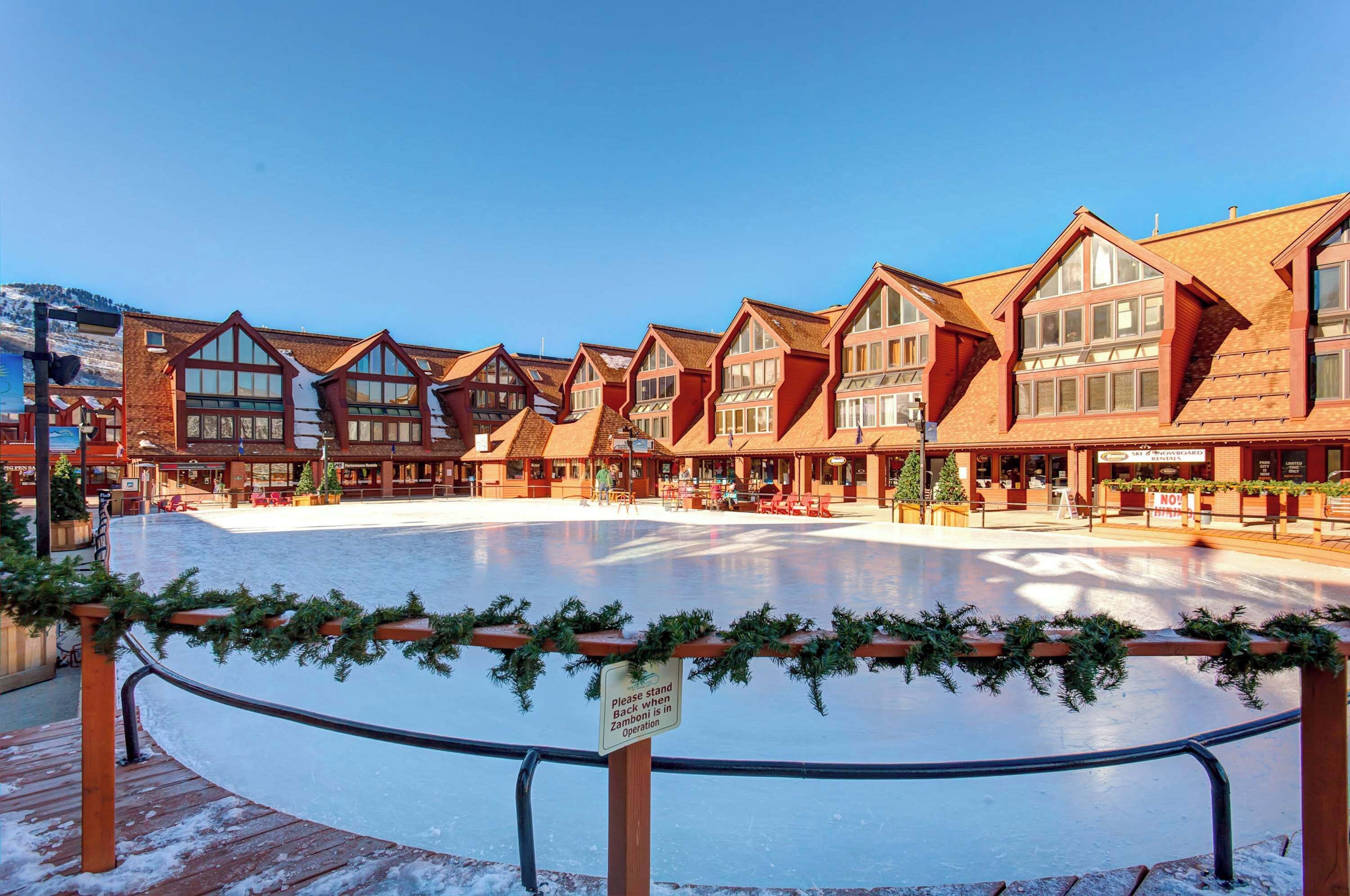 Ein Hotel mit einer großen Eisbahn im Freien, Holzhäusern mit großen Fenstern und einem Schild, das anzeigt, dass die Bahn außer Betrieb ist.