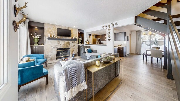Una sala de estar moderna con chimenea, sillones azules, un sofá y una escalera.