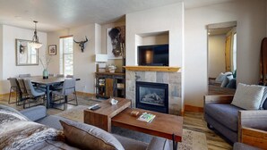 A living room with a fireplace, a dining area, and a sofa. - Redstone Center Gem - Walk to Shops, close to Ski Shuttle Stop (Park City)