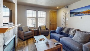 A living room with a fireplace, two sofas, a coffee table, and a painting on the wall. - Redstone Center Gem - Walk to Shops, close to Ski Shuttle Stop (Park City)