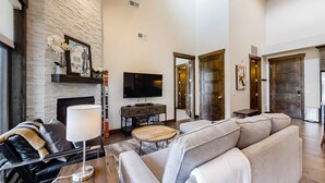 Uma sala de estar moderna com lareira, televisão de tela plana, sofá, mesa de centro e abajur.