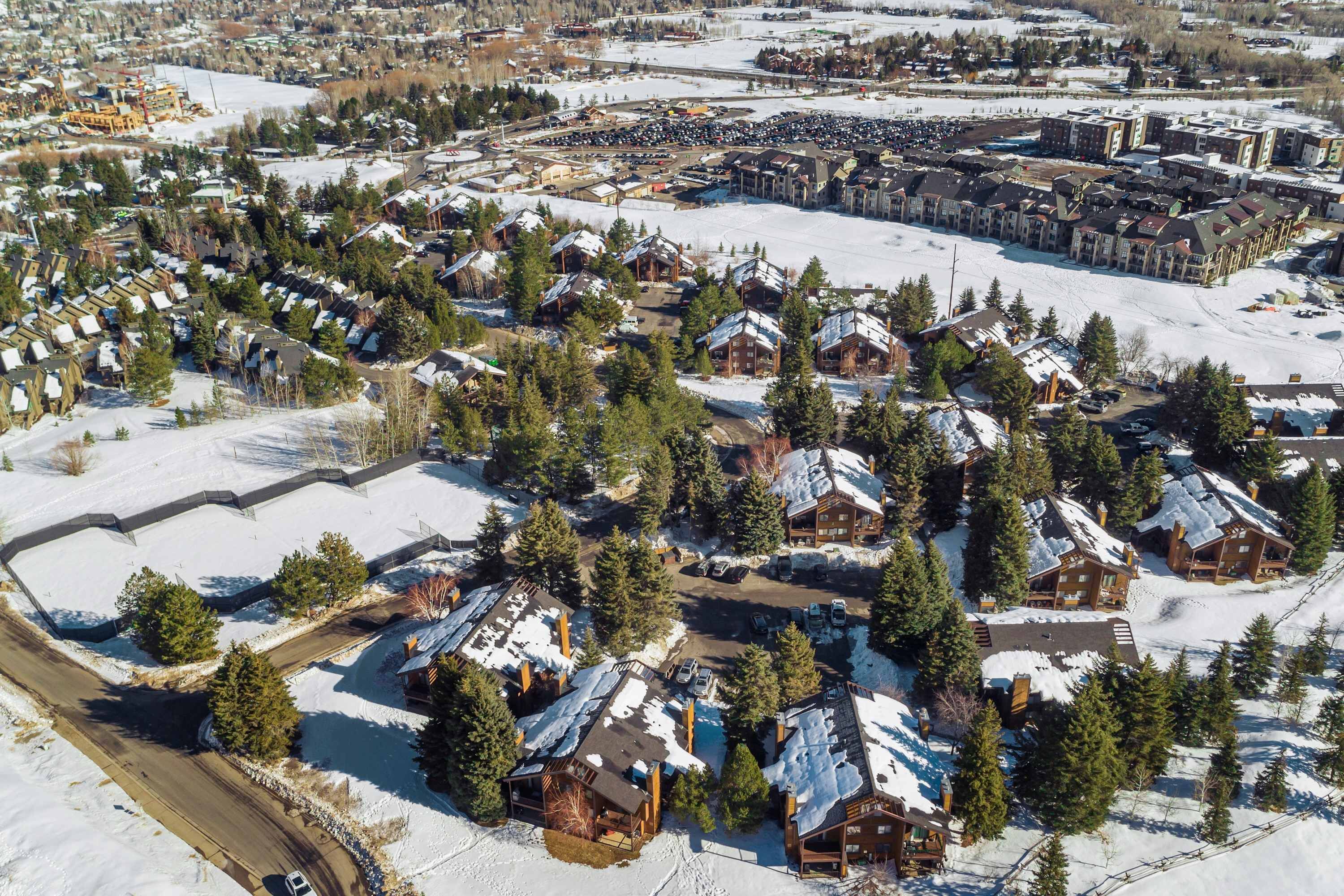 A snow-covered residential area with multiple wooden cabins and a large building complex.