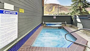Un jacuzzi con un cartel de precaución, vista a la montaña y un muro de madera.